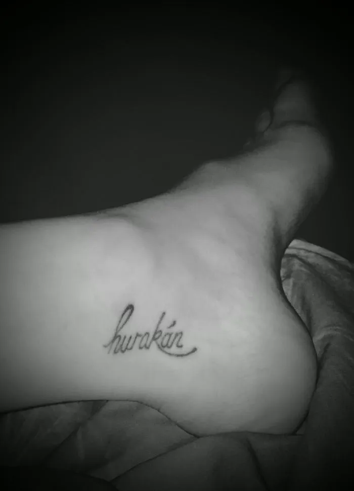 Small foot tattoo in cursive script on the inner side of the foot, showcasing minimalist design.