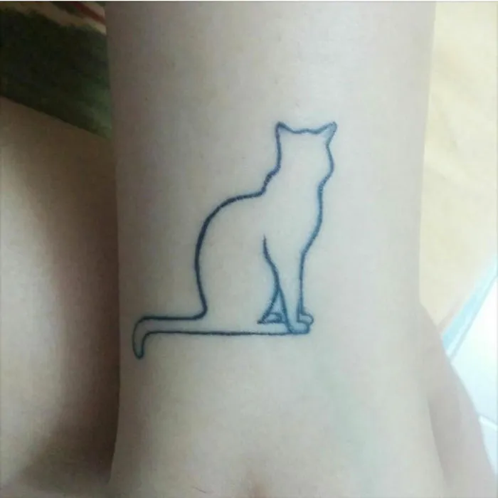 Minimalist small foot tattoo of an outlined cat, showcasing less is more design concept.