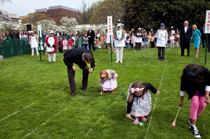 President Barack Obama Cheers On A Young Child As She Rolls Her Egg Toward The Finish Line During The White House Easter Egg Roll