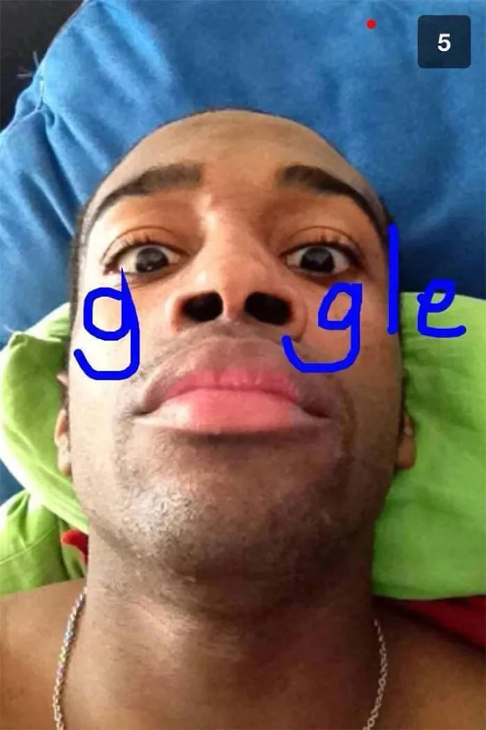 Close-up selfie of a man with "Google" humorously drawn on his face in blue marker.