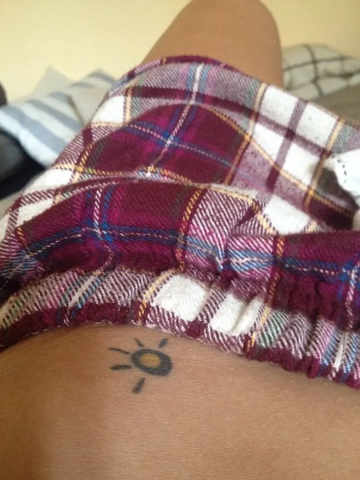 Minimal small foot tattoo of a sun under a plaid blanket, showcasing simplicity in design.