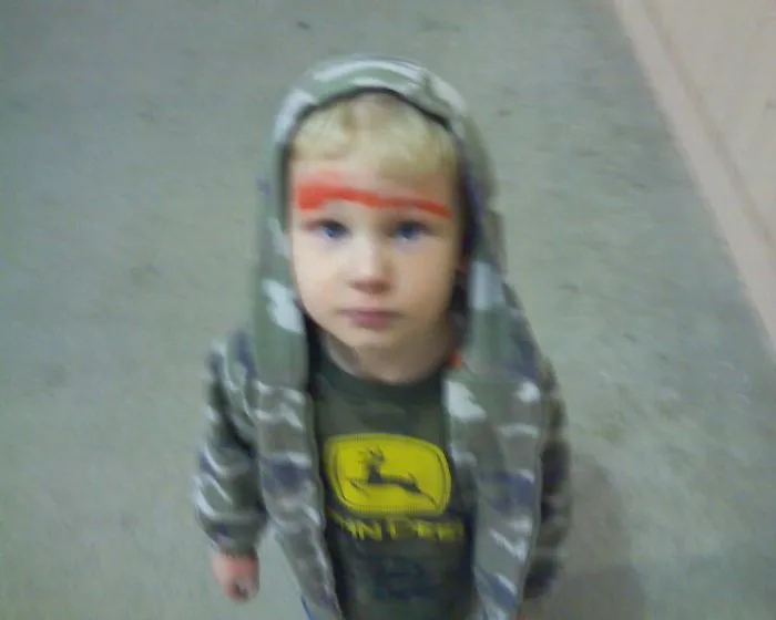 Young boy with face paint wearing striped hoodie indoors