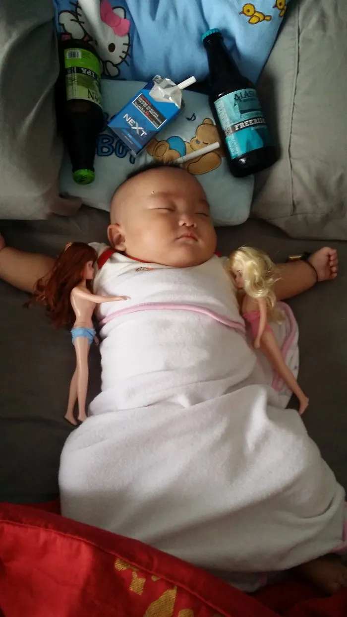 Sleeping baby surrounded by toy dolls and beer bottles, funny kids can't be left alone with their dads