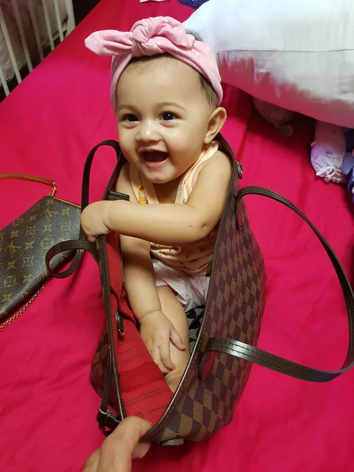 Happy baby sitting inside a handbag showing kids alone with their dads humor