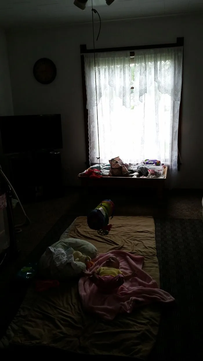 Dimly lit room with baby lying on blanket near window