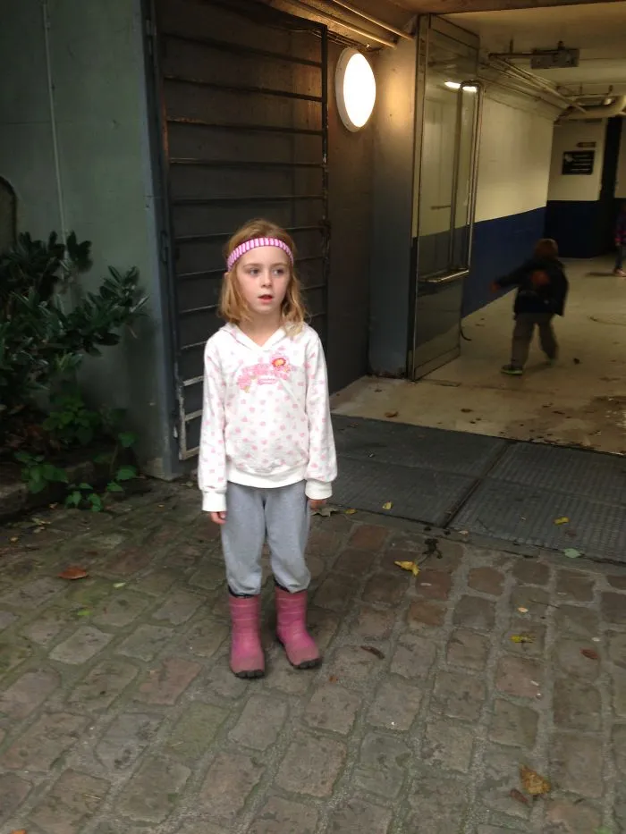 Girl standing outside a building with pink boots showing kids alone with dads