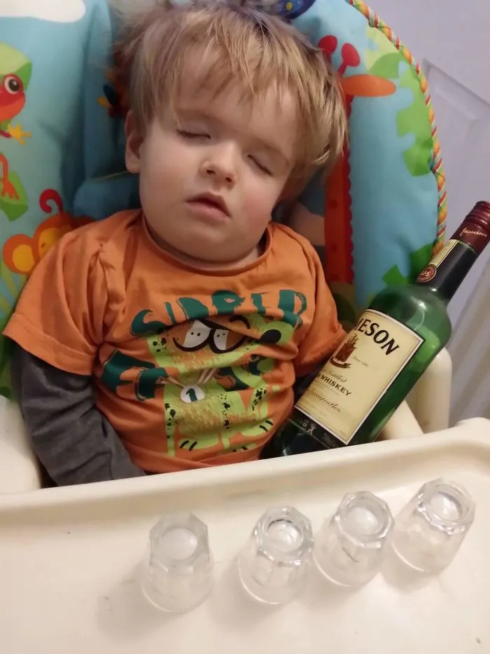 Toddler sleeping in high chair next to a whiskey bottle kids alone with dads