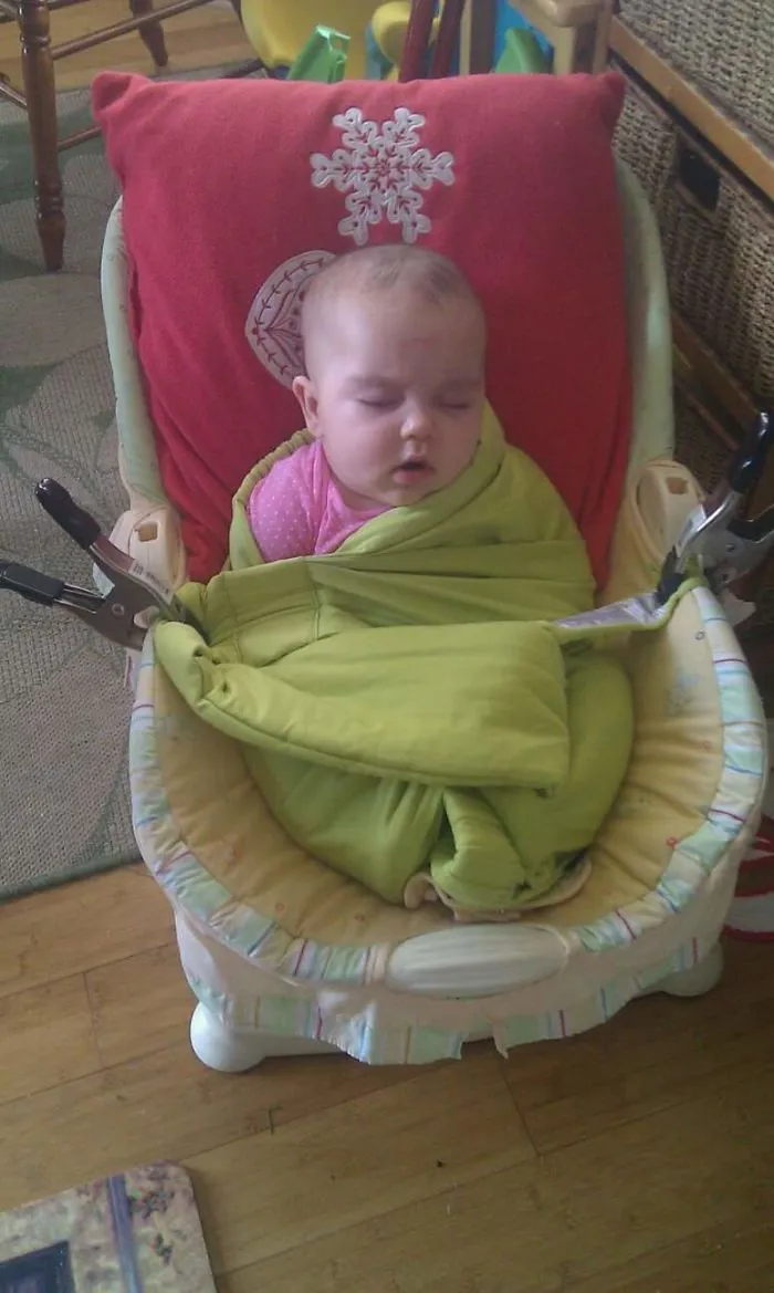 Toddler wrapped in green blanket held by clamps showing why kids can't be left alone with dads