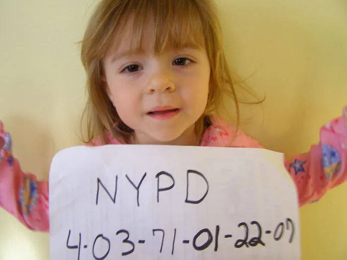Little girl holding a handwritten NYPD sign, funny kids can't be left alone with their dads
