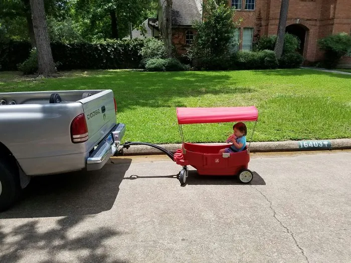 Toddler in wagon attached to truck showing unusual kids transport