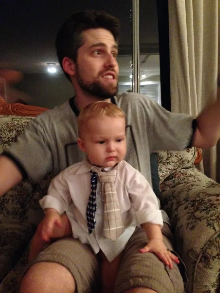 Dad with baby wearing multiple ties sitting on his lap, funny kids can't be left alone with their dads