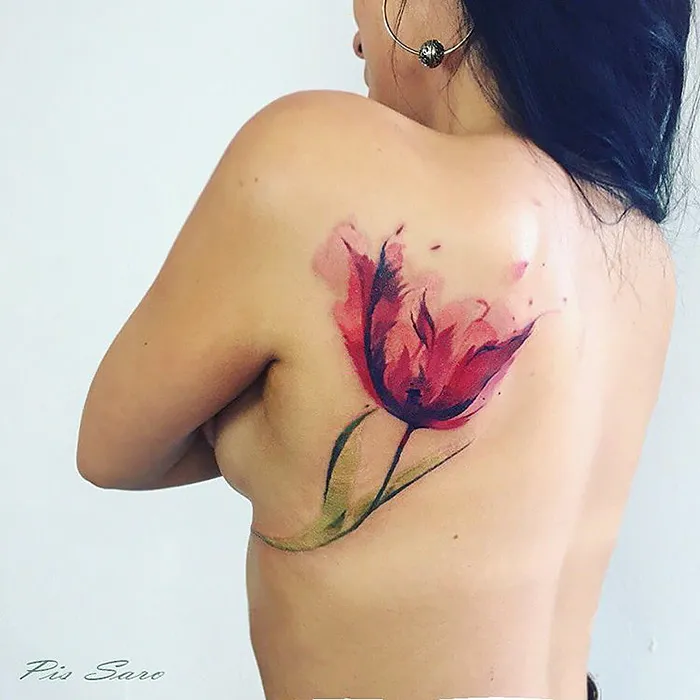 Ethereal nature tattoo of a red flower on a person's back, inspired by changing seasons.