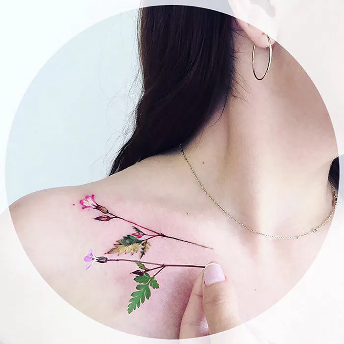Nature tattoo on a shoulder featuring seasonal flowers and leaves.