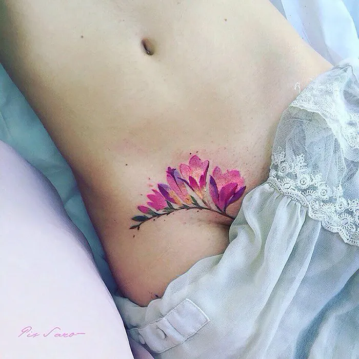 Watercolor flower tattoo on skin, showcasing ethereal nature themes.