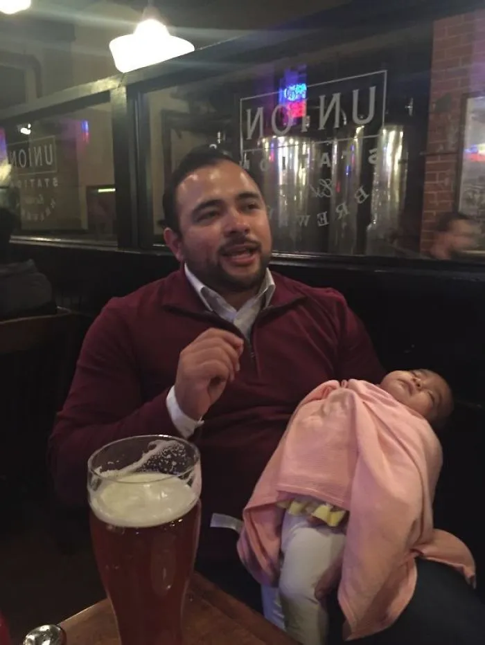 Man holding baby in restaurant with beer glass showing kids cant be left alone with dads