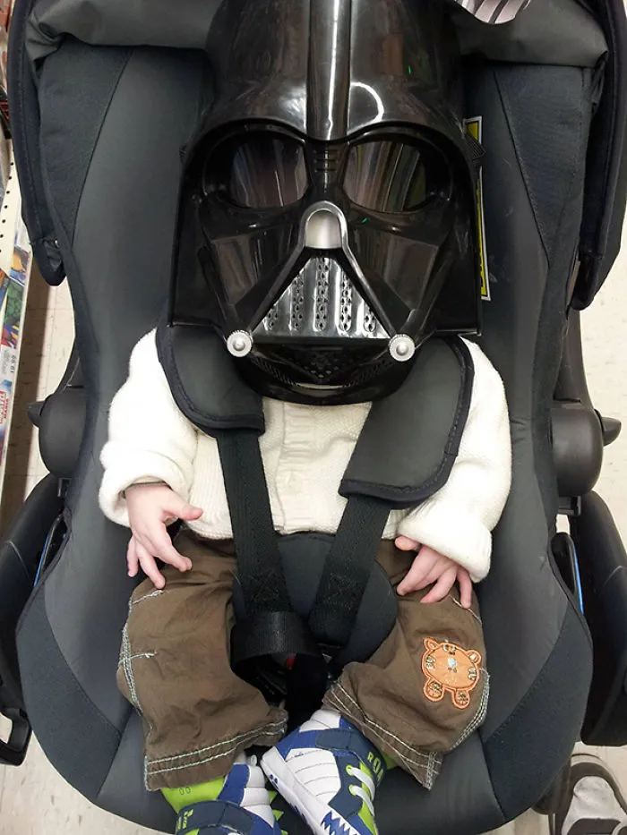 Baby in car seat wearing Darth Vader mask showing kids playtime