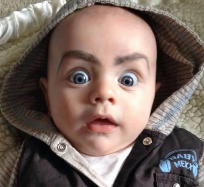 Baby with exaggerated drawn-on eyebrows surprised expression