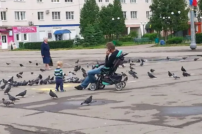 Dad on phone sitting in stroller while child wanders with pigeons reasons kids can't be left alone with dads