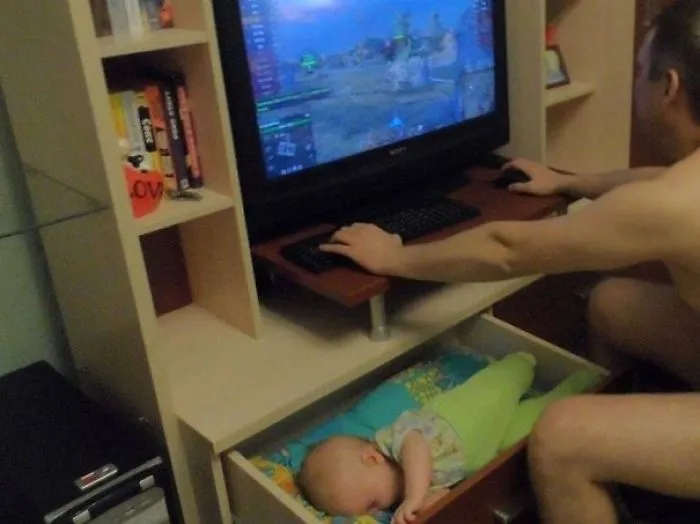 Man gaming while baby sleeps in drawer below reasons kids can't be left alone with dads