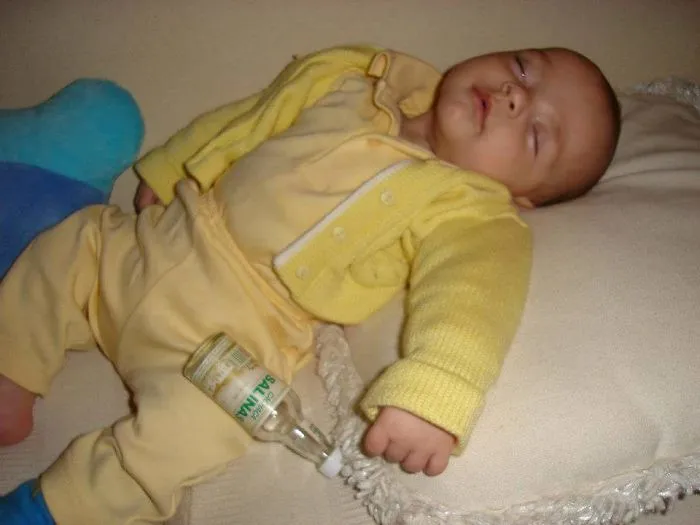 Sleeping baby holding an empty bottle illustrating kids can't be left alone