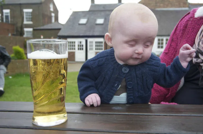 Baby sitting at a pub table beside a pint of beer kids alone with dads