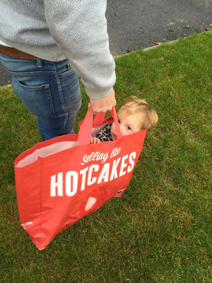 Child sitting inside a red shopping bag outdoors kids alone with dads funny