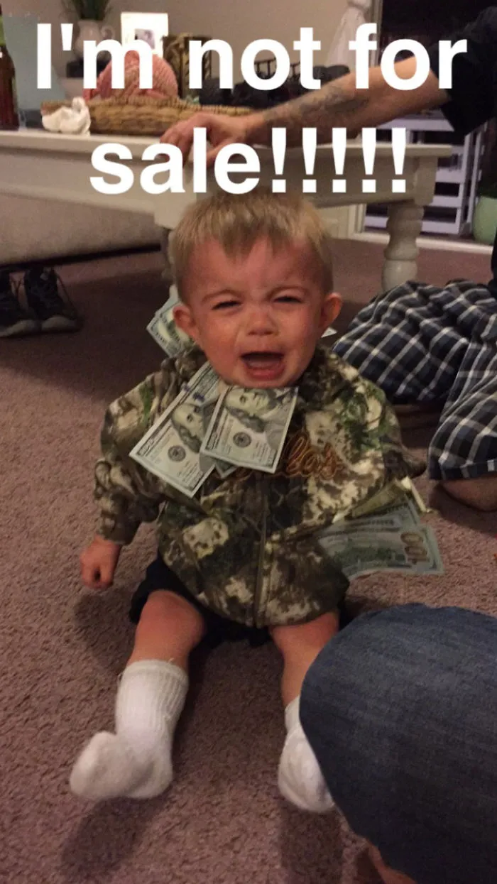 Crying toddler with dollar bills and not for sale sign representing kids can't be left alone with dads