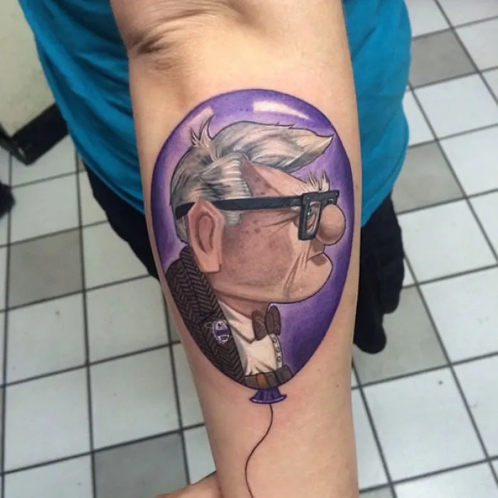 Pixar tattoo of a character inside a purple balloon on forearm.