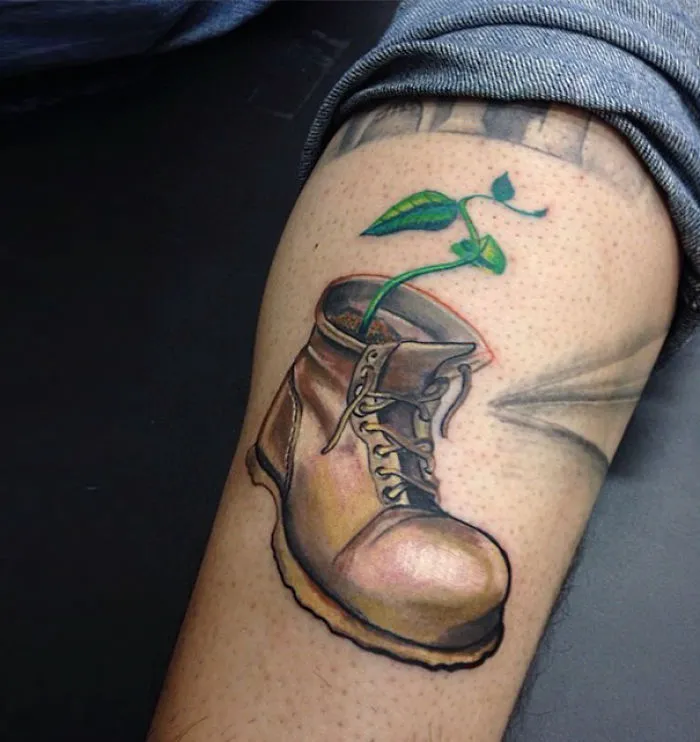Pixar-inspired tattoo featuring a boot with a green plant sprouting, designed with colorful details on forearm skin.