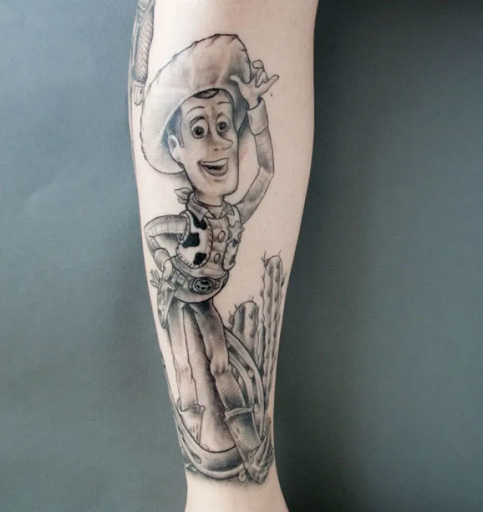 Pixar-inspired tattoo of a cowboy character on a person's forearm, showcasing detailed black and gray shading.