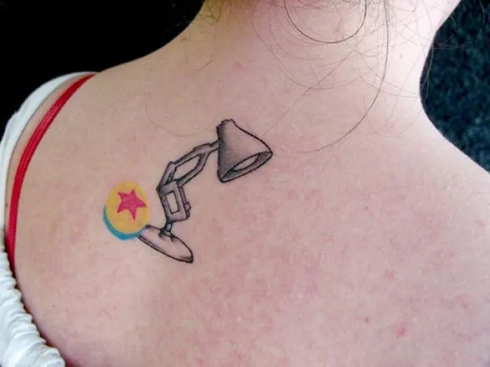 Pixar-inspired tattoo featuring the iconic lamp and ball on a person's back.