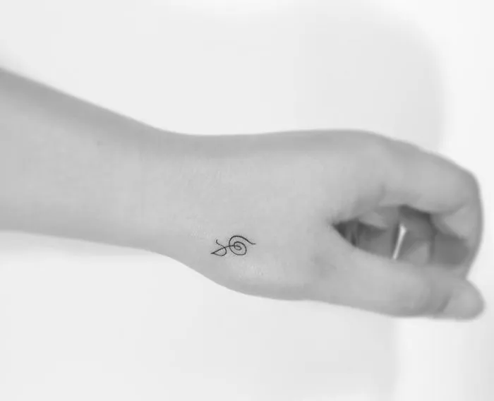 Minimalist tattoo of a small snail design on wrist, created by a Korean artist.
