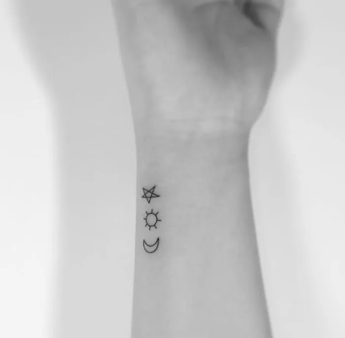 Minimalist tattoos on wrist by Korean artist featuring star, sun, and moon designs.