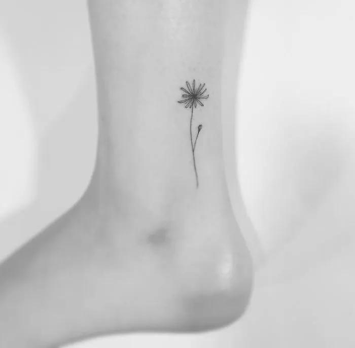 Minimalist tattoo of a small flower on the ankle by a Korean artist.
