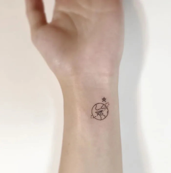 Minimalist tattoo of a small plane and star on a wrist, designed by a Korean artist.
