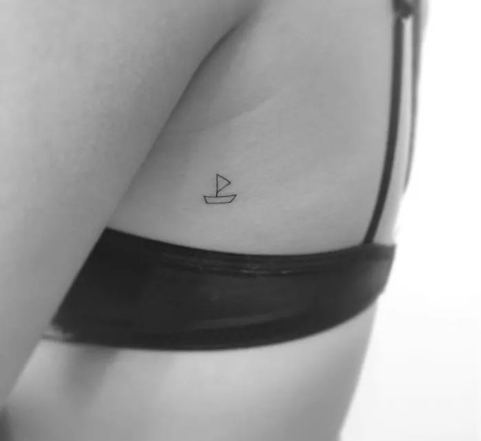 Minimalist tattoo of a small boat on a person's side, created by a Korean artist.