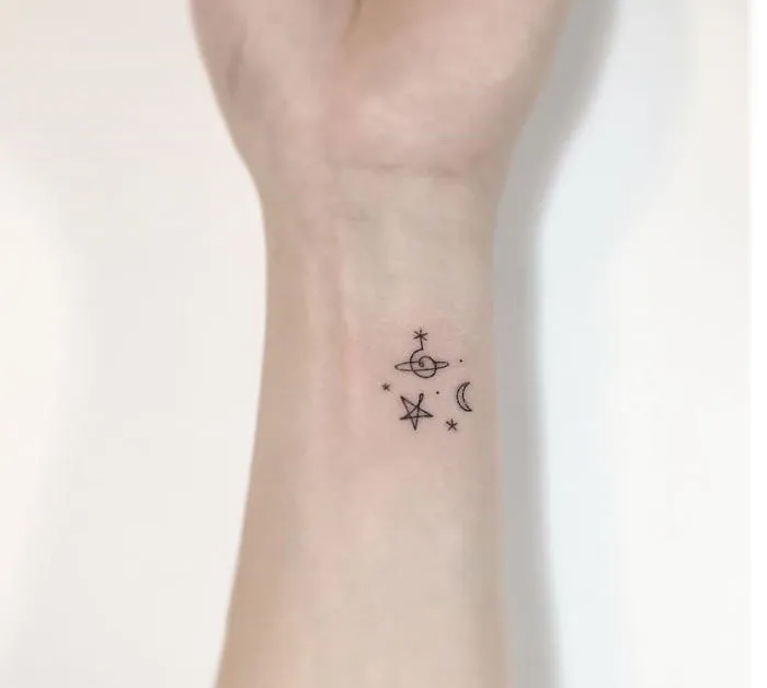 Minimalist tattoo on wrist featuring a star, moon, and planet design by a Korean artist.