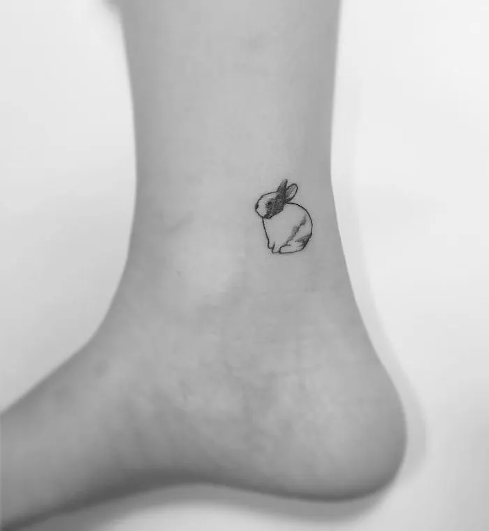 Minimalist tattoo of a small rabbit by a Korean artist on an ankle.