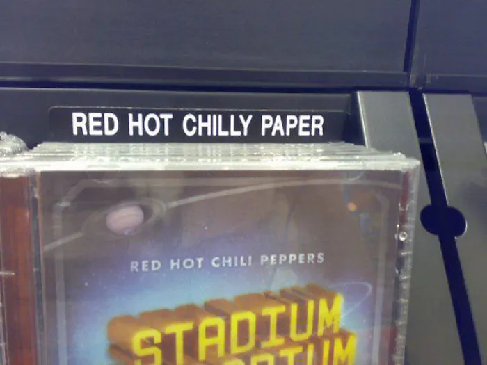 Store shelf label incorrectly reads "Red Hot Chilly Paper" above a Red Hot Chili Peppers album.