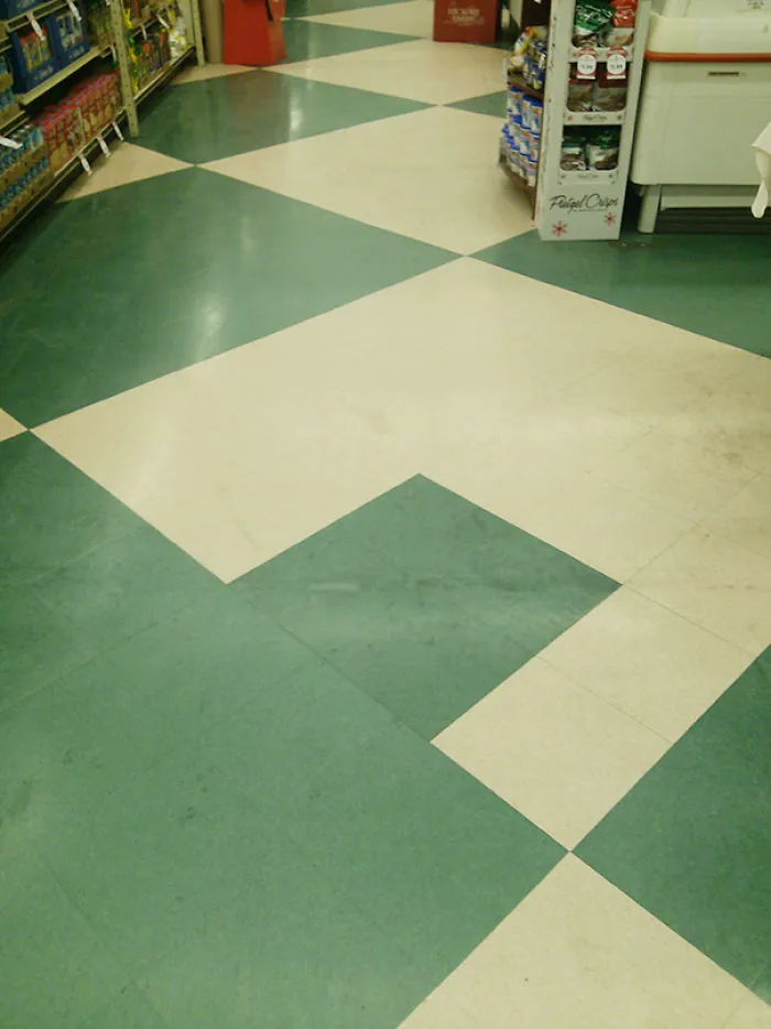 Floor design fail with mismatched green and beige tiles in a store aisle.