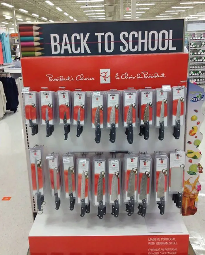 Display of kitchen knives under "Back to School" sign, highlighting a product placement fail.