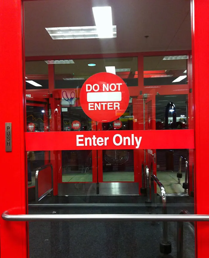 Conflicting "Do Not Enter" and "Enter Only" signs on a red door, illustrating a single job failure.