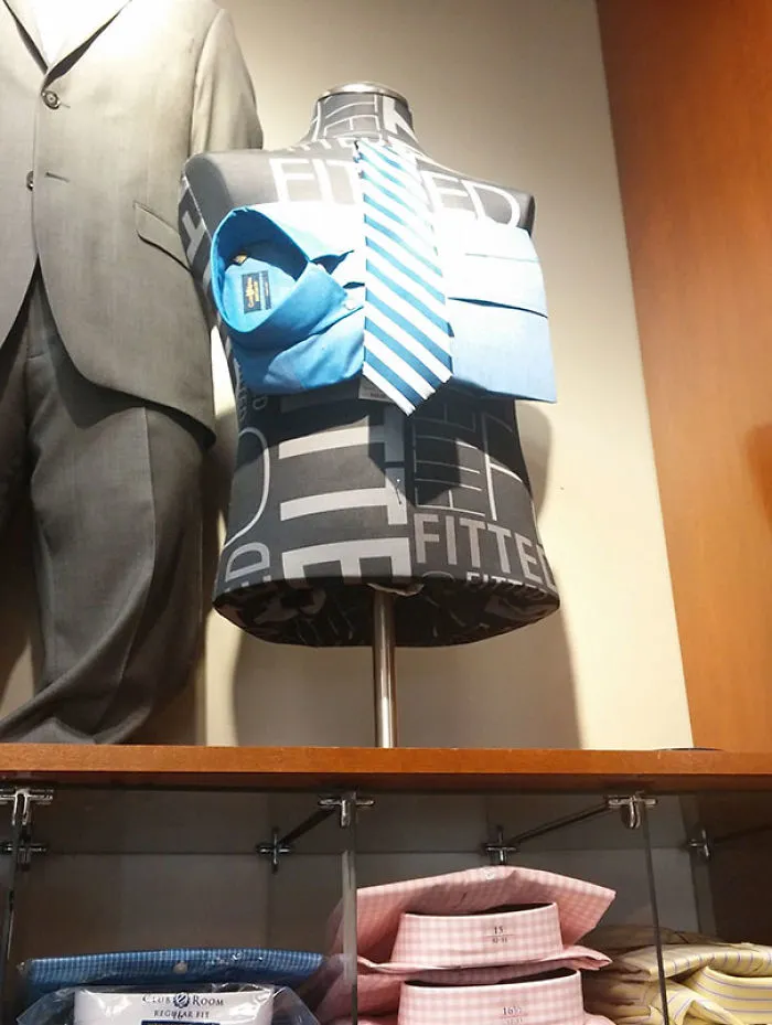 Mannequin with a tie and shirt on its chest, incorrectly assembled, in a clothing store display; failed job execution.