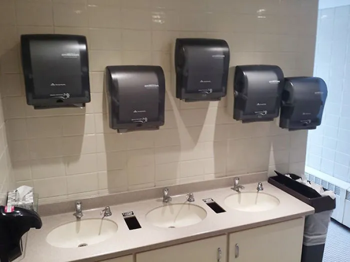 Bathroom sinks with paper towel dispensers poorly placed above each sink.