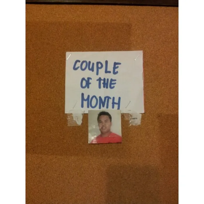 Photo of a single man under a sign reading "Couple of the Month," illustrating an amusing job fail.