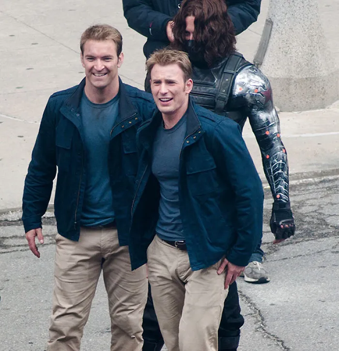 Two men resembling each other on a street set, showcasing Hollywood celebrities’ body doubles during filming.