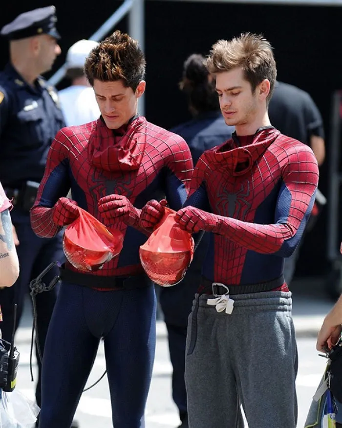 Two men in Spider-Man suits holding helmets, illustrating Hollywood celebrities’ body doubles on set.