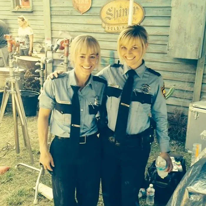 Two women in police uniforms smiling and posing, illustrating Hollywood celebrities’ body doubles on set.