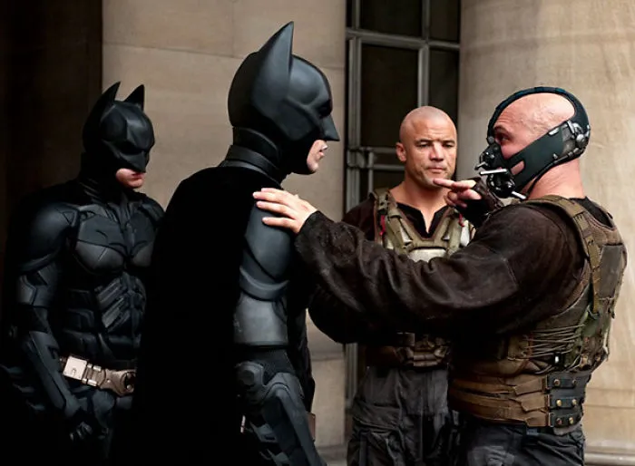 Two Batman characters and actors in tactical gear on set demonstrating body doubles in Hollywood scenes.