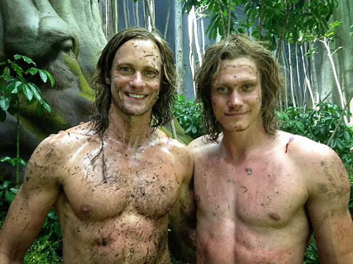 Two shirtless men covered in dirt posing together in a forest scene, highlighting Hollywood celebrities’ body doubles.
